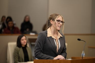 Woman in grey suit jacket speaks to the courtroom 