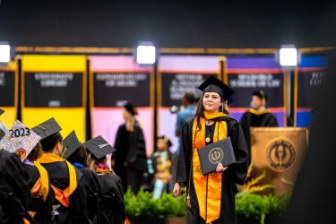 student walking with diploma