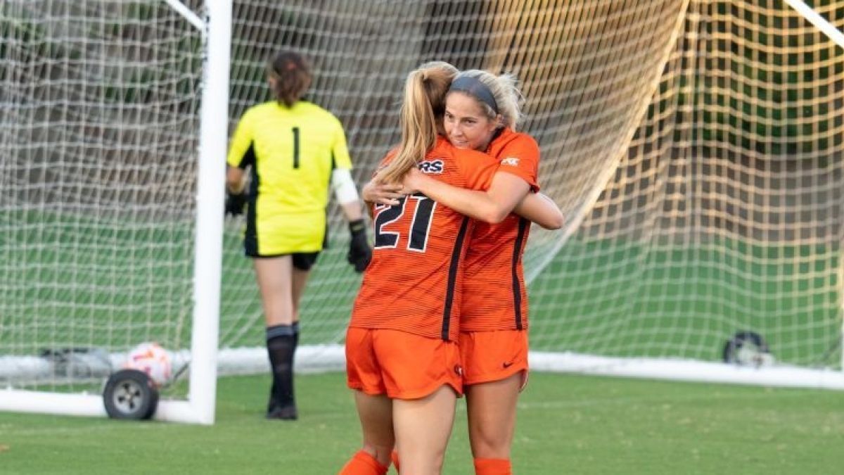 two soccer players hug while standing on the field