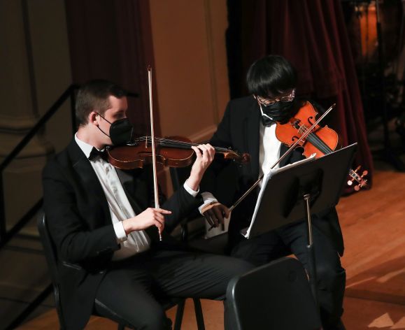 two performers play violins