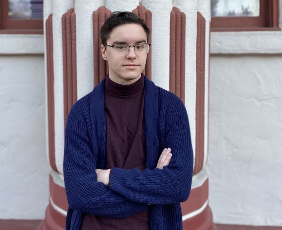 A college student standing by a building