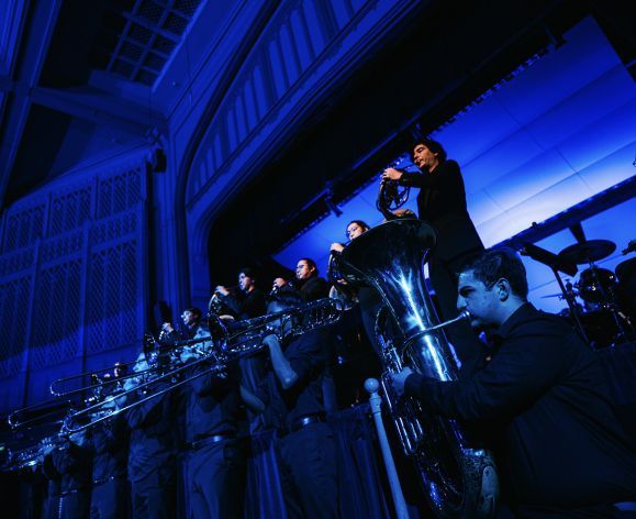 students playing brass instruments under blue light